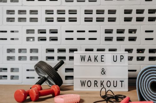 Fitness gear and motivational sign in home gym setup against a brick wall.